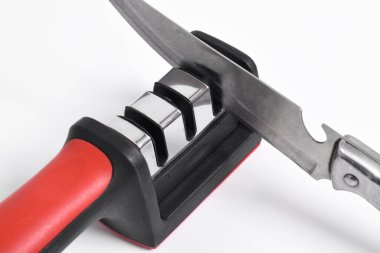 Bıçak ve bıçak keskinleştirici beyaz arka planda izole edilmiş. Elle bıçak bileme, mutfak aletleri.