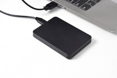 Beyaz arkaplandaki dizüstü bilgisayara bağlı harici yedek disk sürücüsü. USB 3.0 portu ile laptopa bağlanan harici sabit disk