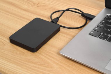 Tahta masadaki dizüstü bilgisayara bağlı harici yedek hard disk. USB 3.0 portu ile laptopa bağlanan harici sabit disk