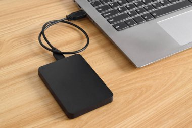 Tahta masadaki dizüstü bilgisayara bağlı harici yedek hard disk. USB 3.0 portu ile laptopa bağlanan harici sabit disk