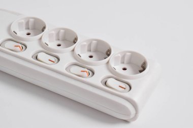 Beyaz arka planda izole edilmiş prizdeki beyaz elektrik prizi, elektrik kablosu, dört priz, bir güç düğmesi ve bağlı bir elektrik prizi.