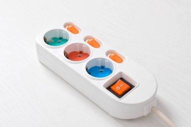 Beyaz arka planda izole edilmiş prizdeki beyaz elektrik prizi, güç kablosu, elektrik uzatma kablosu, üç soket, bir güç düğmesi ve bağlı bir elektrik prizi.