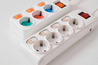 Beyaz arka planda izole edilmiş prizdeki beyaz elektrik prizi, güç kablosu, elektrik uzatma kablosu, güç düğmesi ve bağlı bir elektrik prizi.