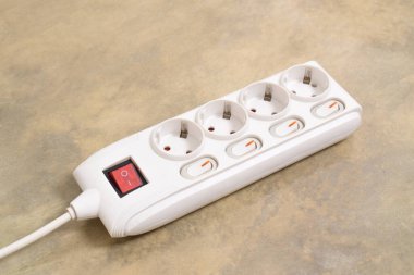 Evdeki prizin prizine beyaz elektrik prizi, güç kablosu, elektrik uzatma kablosu, güç düğmesi ve bağlı bir elektrik prizi.