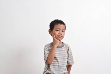 Beyaz arka planda kurnazca poz veren Asyalı bir çocuk resmi. Asyalı bir çocuğun portresi