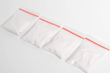 Beyaz arka planda izole edilmiş plastik pakette kokain. Yasadışı uyuşturucu maddeler, beyaz toz, narkotik
