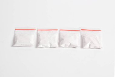 Beyaz arka planda izole edilmiş plastik pakette kokain. Yasadışı uyuşturucu maddeler, beyaz toz, narkotik