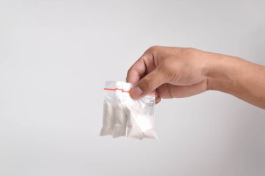 Beyaz arka planda izole edilmiş plastik pakette el yapımı kokain. Yasadışı uyuşturucu maddelerinin ve uyuşturucuların gösterimi