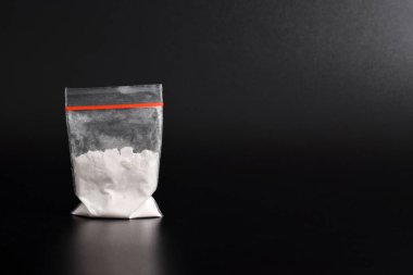 Siyah arka planda izole edilmiş plastik pakette kokain. Yasadışı uyuşturucu maddelerinin ve uyuşturucuların gösterimi
