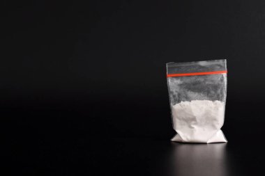 Siyah arka planda izole edilmiş plastik pakette kokain. Yasadışı uyuşturucu maddelerinin ve uyuşturucuların gösterimi