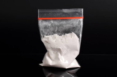Siyah arka planda izole edilmiş plastik pakette kokain. Yasadışı uyuşturucu maddelerinin ve uyuşturucuların gösterimi
