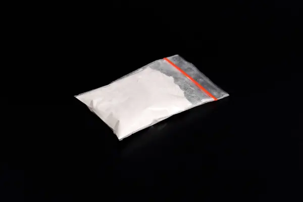 Siyah arka planda izole edilmiş plastik pakette kokain. Yasadışı uyuşturucu maddelerinin ve uyuşturucuların gösterimi