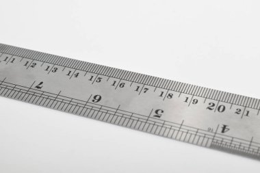 Beyaz arka planda demir cetvel. Paslanmaz çelik cetvel. Kırtasiye malzemeleri ve metal çelikten yapılmış iş aletleri. Seçici odak, beyaz arkaplanda izole