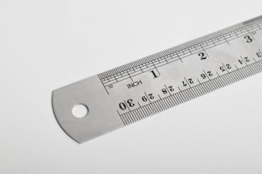 Beyaz arka planda demir cetvel. Paslanmaz çelik cetvel. Kırtasiye malzemeleri ve metal çelikten yapılmış iş aletleri. Seçici odak, beyaz arkaplanda izole