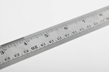 Beyaz arka planda demir cetvel. Paslanmaz çelik cetvel. Kırtasiye malzemeleri ve metal çelikten yapılmış iş aletleri. Seçici odak, beyaz arkaplanda izole