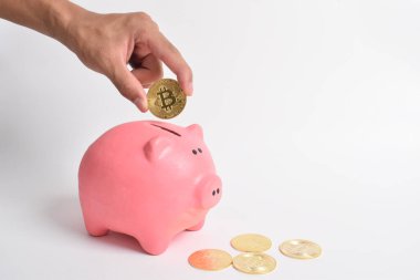 Adamın eli beyaz arka planda izole edilmiş pembe kumbara içine bitcoin koyar. biraz para BTC yeni sanal elektronik para, yatırım konsepti. Boşluğu kopyala