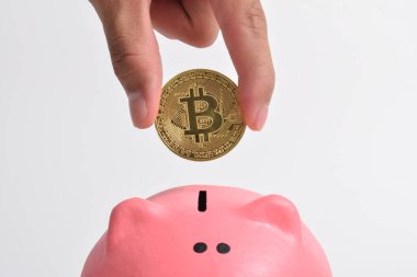 Adamın eli beyaz arka planda izole edilmiş pembe kumbara içine bitcoin koyar. biraz para BTC yeni sanal elektronik para, yatırım konsepti. Boşluğu kopyala