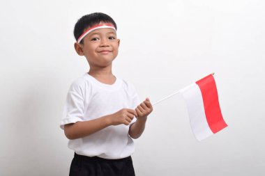 Endonezya Bağımsızlık Günü 'nü kutlamak için beyaz arka planda Endonezya bayrağını tutan tatlı küçük Asyalı çocuk..