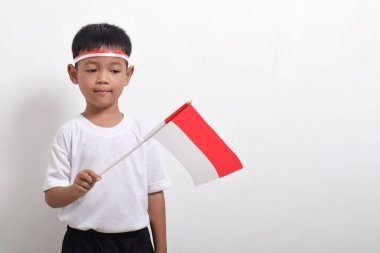 Endonezya Bağımsızlık Günü 'nü kutlamak için beyaz arka planda Endonezya bayrağını tutan tatlı küçük Asyalı çocuk..