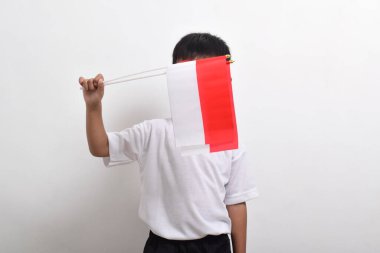 Endonezya 'nın Bağımsızlık Günü' nü kutlamak için 17 Ağustos 'ta beyaz arka planda izole edilmiş Endonezya bayrağını tutan sevimli küçük Asyalı çocuk..
