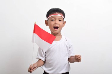 17 Ağustos 'ta beyaz arka planda izole edilmiş, Endonezya Bağımsızlık Günü' nü kutlamak için bayrak takan mutlu yüzlü, tatlı Asyalı çocuk..