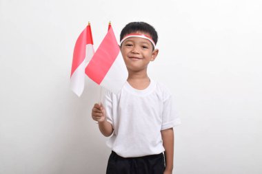 Endonezya 'nın Bağımsızlık Günü' nü kutlamak için 17 Ağustos 'ta beyaz arka planda izole edilmiş Endonezya bayrağını tutan sevimli küçük Asyalı çocuk..