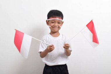 Endonezya 'nın Bağımsızlık Günü' nü kutlamak için 17 Ağustos 'ta beyaz arka planda izole edilmiş Endonezya bayrağını tutan sevimli küçük Asyalı çocuk..