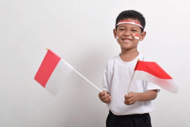 Endonezya 'nın Bağımsızlık Günü' nü kutlamak için 17 Ağustos 'ta beyaz arka planda izole edilmiş Endonezya bayrağını tutan sevimli küçük Asyalı çocuk..