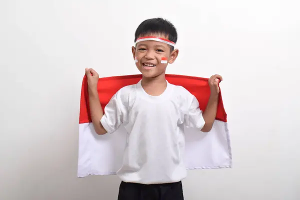 stock image Cute little Asian boy wearing flag headband and holding Indonesian flag to celebrate Indonesian Independence Day on August 17 isolated on white background.