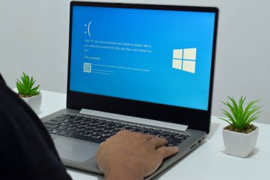 Pasuruan, Endonezya - 20 Temmuz 2024: Dizüstü bilgisayarlı bir adam mavi ölüm ekranını veya BSOD 'u monitörde gösterir. Hatalı Microsoft Windows işletim sistemi. Mavi ölüm perdesi