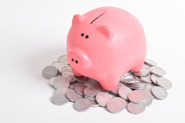 Beyaz arka planda izole edilmiş bozuk paraların üzerindeki pembe kumbara. Emeklilik ve gelecek planlama konsepti için para biriktirme.