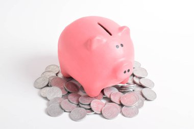 Beyaz arka planda izole edilmiş bozuk paraların üzerindeki pembe kumbara. Emeklilik ve gelecek planlama konsepti için para biriktirme.