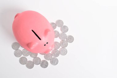 Pembe kumbara ve beyaz arka planda izole edilmiş madeni paralar, üst manzara. Yatırım bütçesi tasarruf emekliliği, finans, para, bankacılık konsepti. Boşluğu kopyala