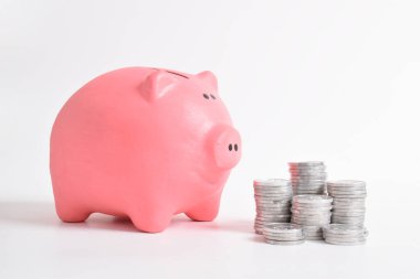 Pembe kumbara ve beyaz arka planda izole edilmiş bir yığın bozuk para. Yatırım bütçesi tasarruf emekliliği, finans, para, bankacılık konsepti. Boşluğu kopyala