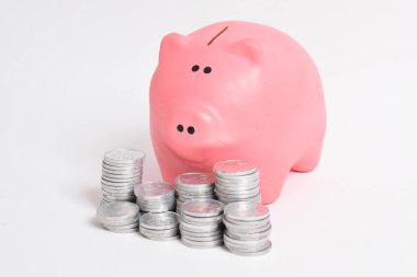 Pembe kumbara ve beyaz arka planda izole edilmiş bir yığın bozuk para. Yatırım bütçesi tasarruf emekliliği, finans, para, bankacılık konsepti. Boşluğu kopyala
