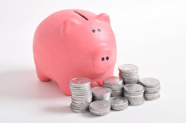Pembe kumbara ve beyaz arka planda izole edilmiş bir yığın bozuk para. Yatırım bütçesi tasarruf emekliliği, finans, para, bankacılık konsepti. Boşluğu kopyala