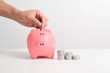 Beyaz arka planda izole edilmiş kumbaraya bozuk para koyan bir adam. İş finansmanı, tasarruf ve yatırım konsepti. Para biriktirmek için kumbaraya para koyuyorlar.