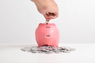 Beyaz arka planda izole edilmiş ve fotokopi alanı olan kumbaralara para koyuyorlar. Tasarruf, yatırım ve finans kavramı.