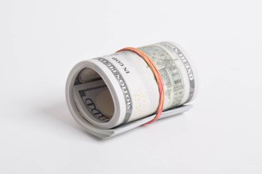 Bundle of money roll of dollars isolated on white background, stack of one hundred dollars American cash money bills rolled up with rubber band.