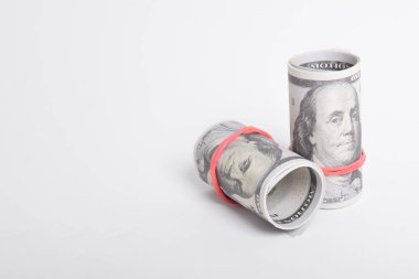 Kırmızı lastikle sarılmış dolar rulosu. Beyaz arka planda izole edilmiş 100 dolarlık banknotlar. Yuvarlanan Amerikan doları banknotları