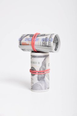 Kırmızı lastikle sarılmış dolar rulosu. Beyaz arka planda izole edilmiş 100 dolarlık banknotlar. Yuvarlanan Amerikan doları banknotları