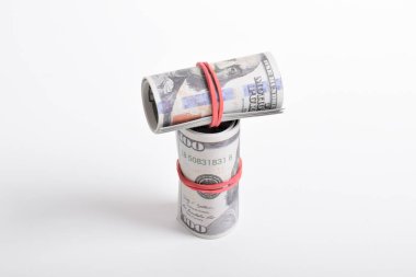 Kırmızı lastikle sarılmış dolar rulosu. Beyaz arka planda izole edilmiş 100 dolarlık banknotlar. Yuvarlanan Amerikan doları banknotları