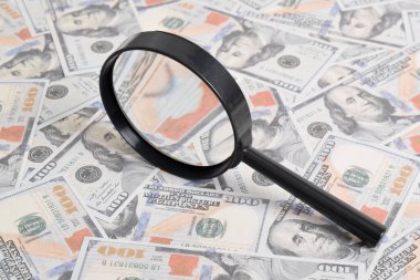 Masadaki bir tomar doların arka planında büyüteç var. Amerikan doları dokusu. Banknotlar. Amerikan parası