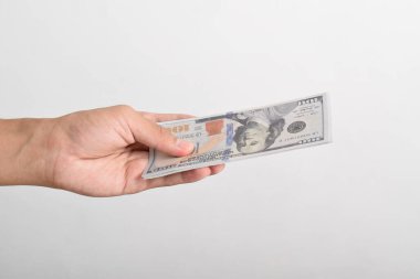 Adam elini dolar banknotuna uzatıyor. El ele tutuşan dolar, beyaz arka planda izole edilmiş 100 dolar banknot.