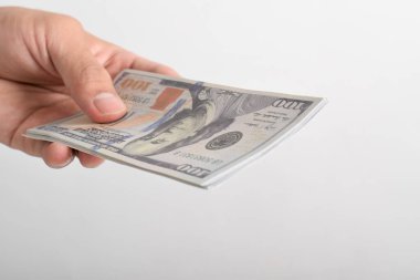 Adam elini dolar banknotuna uzatıyor. El ele tutuşan dolar, beyaz arka planda izole edilmiş 100 dolar banknot.