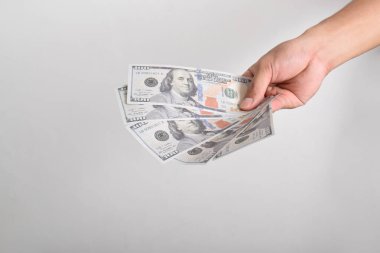 Adam elini dolar banknotuna uzatıyor. El ele tutuşan dolar, beyaz arka planda izole edilmiş 100 dolar banknot.