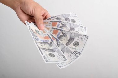 Adam elini dolar banknotuna uzatıyor. El ele tutuşan dolar, beyaz arka planda izole edilmiş 100 dolar banknot.