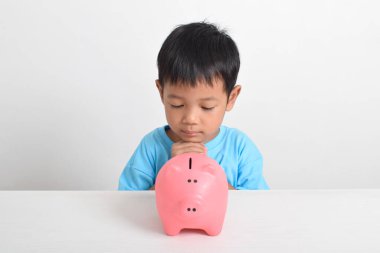 Beyaz arka planda izole edilmiş domuz kumbarasına umut besleyen sevimli Asyalı çocuk. Çocuk konsepti için para biriktiriyorum. Tasarruf etmeyi öğren. Para, finans ve sigorta kavramı
