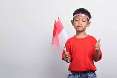 Kırmızı tişörtlü heyecanlı Asyalı çocuk beyaz arka planda izole edilmiş, işaret veriyor. Endonezya Bağımsızlık Günü konsepti.