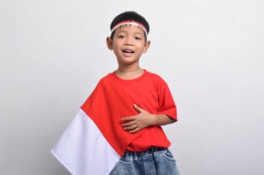 Endonezya bayrağı omzunda, beyaz arka planda soyutlanmış bir şekilde mutlu bir şekilde gülümseyen Asyalı çocuk. Endonezya Bağımsızlık Günü konsepti.